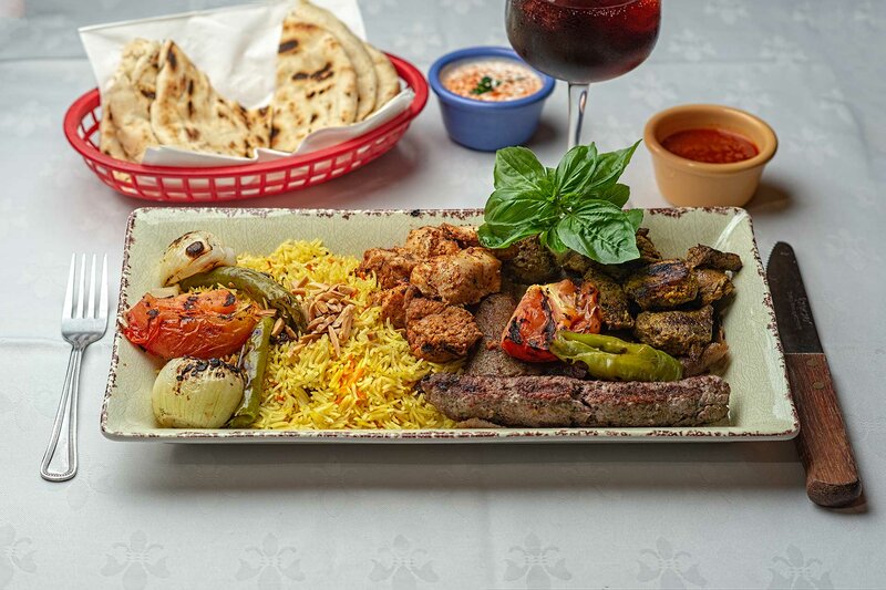 Plated grilled chicken, lamb kabob, beef gyro and kufta kabob with side of rice and vegetables