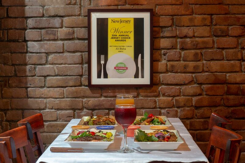 Restaurant dining room with plated entrees on set table for four with picture of 35th annual Jersey Choice award